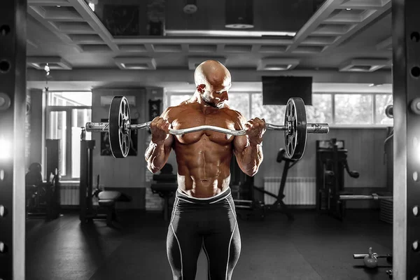 Hombre musculoso ejercitándose en el gimnasio haciendo ejercicios con pesas en bíceps, fuertes abdominales masculinos desnudos del torso —  Fotos de Stock