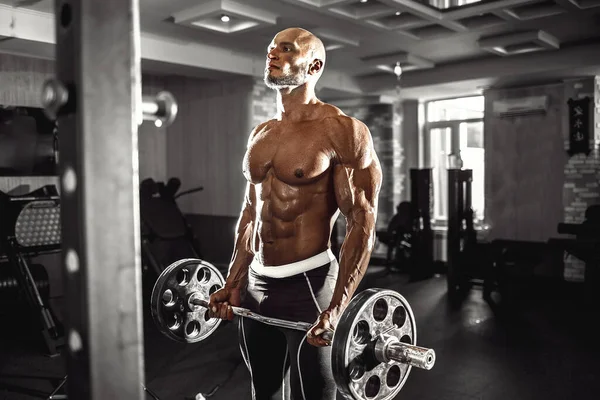 М'язистий чоловік, який працює в тренажерному залі, виконує вправи з гантелями на біцепсах, сильний чоловік голий торс abs — стокове фото