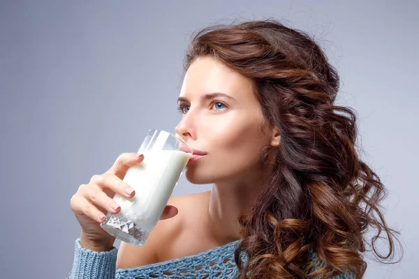 Happy young woman drinking milk over grey background Royalty Free Stock Photos