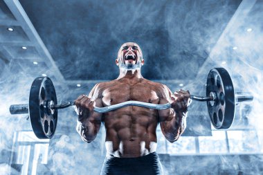 Spor salonunda spor yapan kaslı bir adam, pazularıyla egzersiz yapıyor. Güçlü erkek, çıplak karın kasları var.