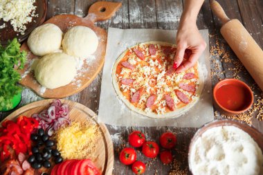 Aşçı mutfakta, pizzanın malzemelerini koyuyor. Pizza konsepti. Gıda üretimi ve teslimatı