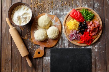 Tahta masadaki malzemeli pizza hamuru.