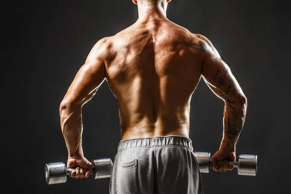 Vista posterior del entrenamiento del culturista con mancuerna aislada en negro — Foto de Stock