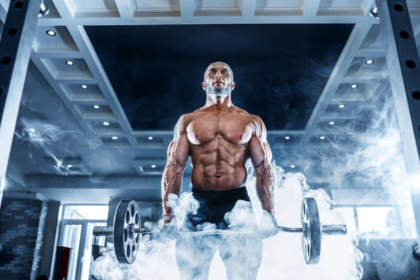 Homem musculoso trabalhando fora no ginásio fazendo exercícios com halteres no bíceps, abdominais fortes tronco nu masculino — Fotografia de Stock