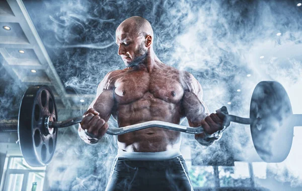 Homem musculoso trabalhando fora no ginásio fazendo exercícios com halteres no bíceps, abdominais fortes tronco nu masculino — Fotografia de Stock