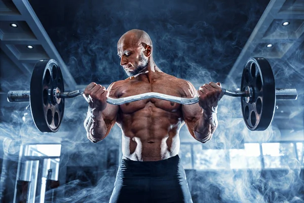 Spierman aan het sporten in de sportschool doet oefeningen met halters bij biceps, sterke mannelijke naakte bovenbuik — Stockfoto