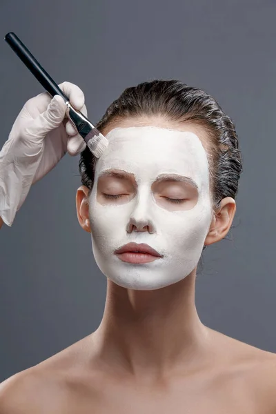 Krásná dívka je aplikována bílá kosmetická maska z černých teček. Izolovat, studio — Stock fotografie