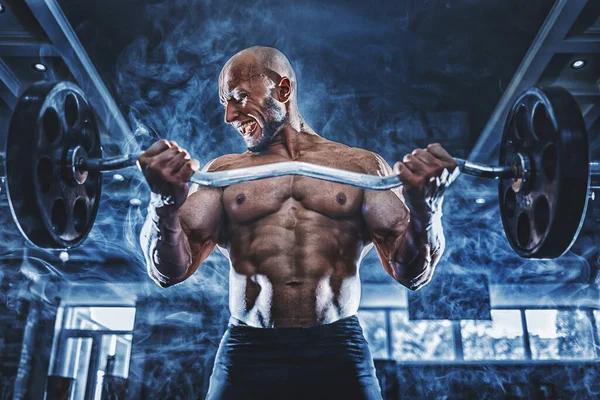 Hombre musculoso ejercitándose en el gimnasio haciendo ejercicios con pesas en bíceps, fuertes abdominales masculinos desnudos del torso —  Fotos de Stock