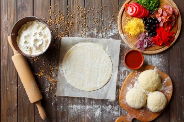 Tahta masadaki malzemeli pizza hamuru.