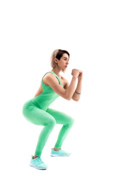 Whit 'te izole edilmiş çömelme hareketleri yapan atletik bir kadının stüdyo fotoğrafı.