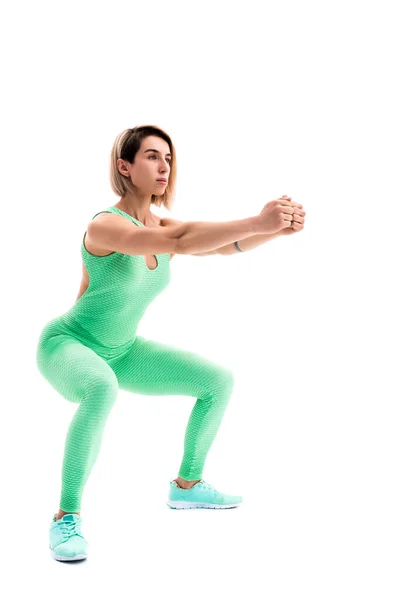 Studio shot of an athletic woman doing squats isolated over whit — Stock Photo, Image