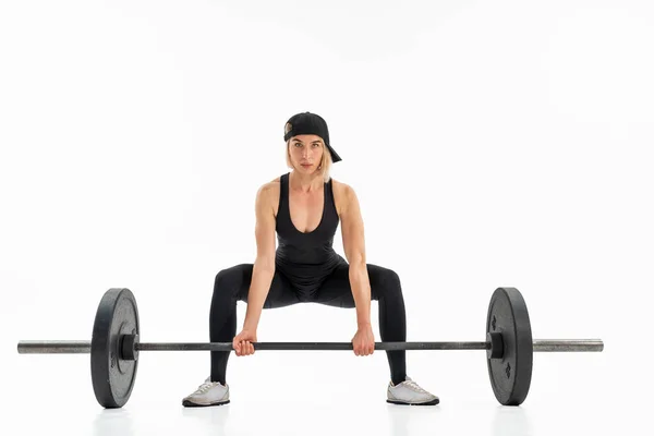 Jonge vrouw doet deadlift met een lange halter geïsoleerd op wit — Stockfoto