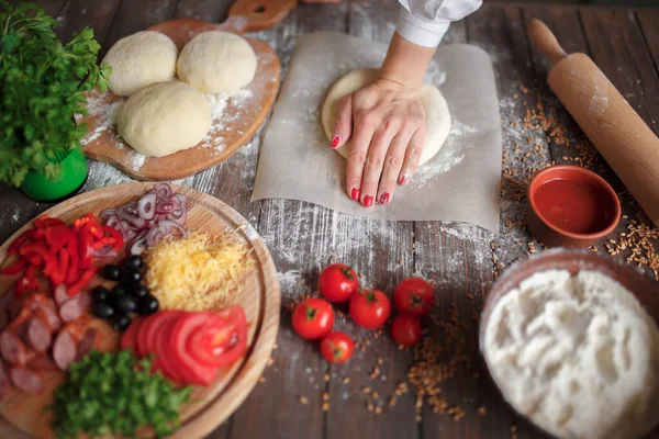 Mulher amassa a massa com as mãos enquanto cozinha — Fotografia de Stock