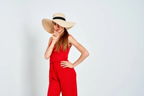 Девушка в солнечной шляпе, стоящая на белом фоне в студии в элегантном красном. — стоковое фото