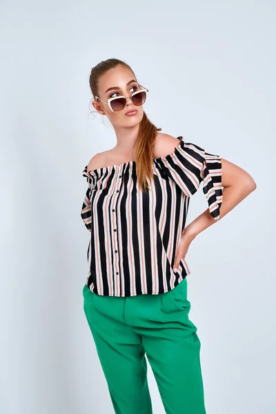 Beautiful young girl in striped shirt and green trousers isolated on white background — Stock Photo, Image