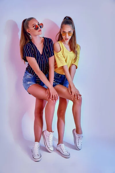 Dos adolescentes en gafas de sol y ropa de verano posando en estudio sobre fondo blanco —  Fotos de Stock