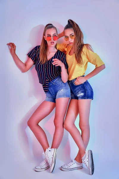 Dos adolescentes en gafas de sol y ropa de verano posando en estudio sobre fondo blanco —  Fotos de Stock