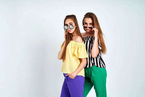 Twee jonge vrouwen in stijlvolle kleding mode schoonheid studio schot op witte achtergrond — Stockfoto