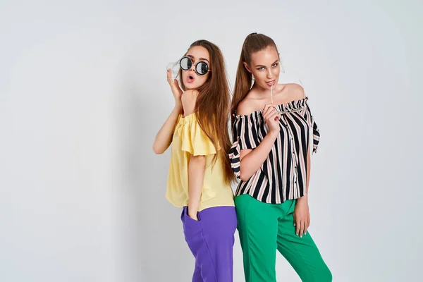Дві молоді жінки в стильному одязі модна студія краси знята на білому тлі — стокове фото