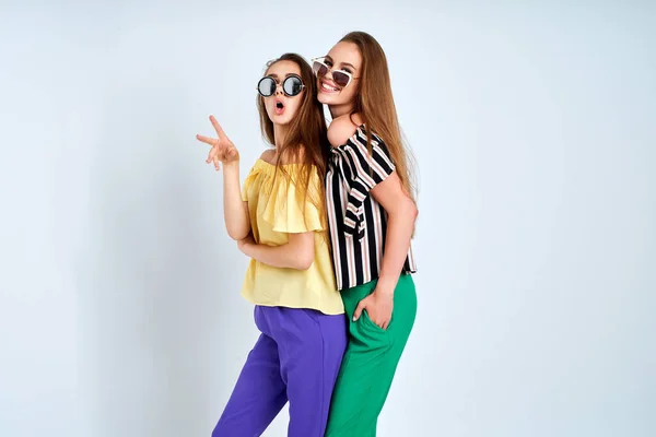 Twee jonge vrouwen in stijlvolle kleding mode schoonheid studio schot op witte achtergrond — Stockfoto