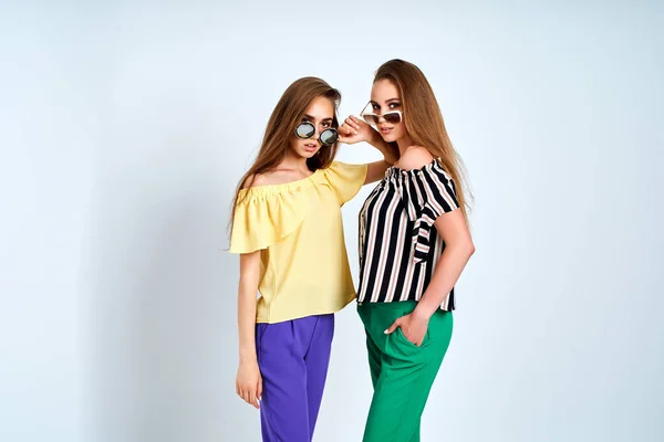 Twee jonge vrouwen in stijlvolle kleding mode schoonheid studio schot op witte achtergrond — Stockfoto