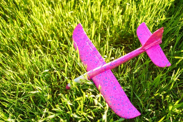 Ein rosafarbenes Kinderflugzeug aus Plastik liegt im Gras — Stockfoto