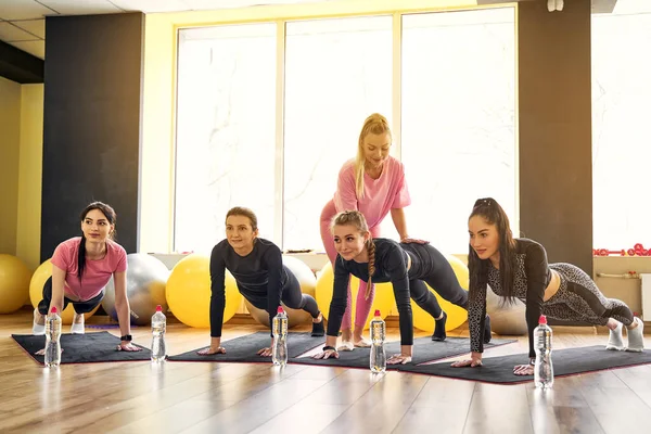 Grupp unga kvinnor gör planka tillsammans i gymmet — Stockfoto