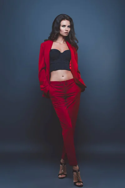 Modelo de moda en traje rojo, hermosa mujer joven. Grabado en estudio. Fondo azul. —  Fotos de Stock