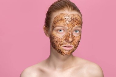 Güzel genç bir kadının yüzünde yüz temizleme maskesi. Organik doğal kozmetoloji. Pembe stüdyo arka planı.