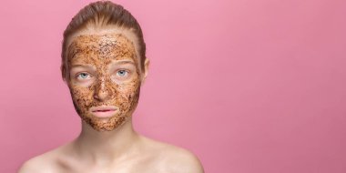 Güzel genç bir kadının yüzünde yüz temizleme maskesi. Organik doğal kozmetoloji. Pembe stüdyo arka planı.