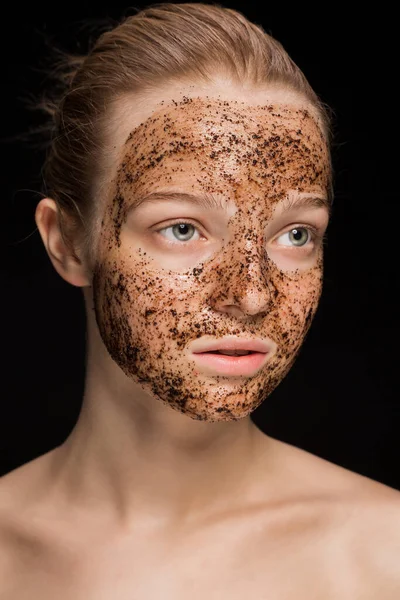 Skin scrub Coffee grounds mask on the face of a beautiful young woman Organic natural cosmetology dark studio background Isolate