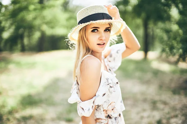 Schöne zarte junge Frau in Sommerkleid und Strohhut, die draußen posiert. Herrlich warmer Sommertag — Stockfoto
