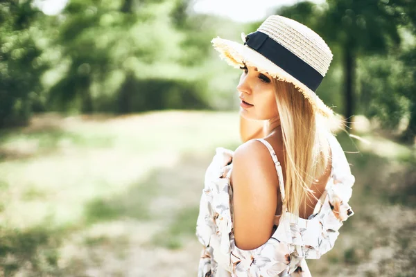 Hermosa tierna joven en vestido de verano y sombrero de paja posando al aire libre. Impresionante día de verano cálido —  Fotos de Stock