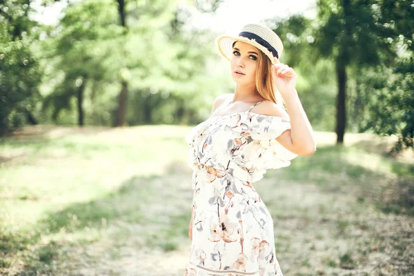 Bela jovem mulher macia em vestido de verão e chapéu de palha posando ao ar livre. Impressionante dia quente de verão — Fotografia de Stock