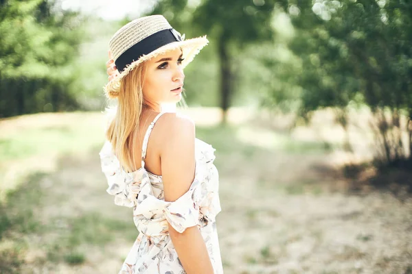 Bela jovem mulher macia em vestido de verão e chapéu de palha posando ao ar livre. Impressionante dia quente de verão — Fotografia de Stock