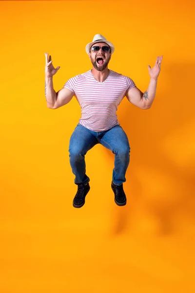 Excited young bearded fitness sporty guy in hat and sunglasses Jump very emotionally isolated on yellow background — Stock Photo, Image