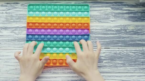 Criança brincar com pop-lo brinquedo sensorial. Prensas em colorido arco-íris squishy bolhas de silicone macio. Alívio de estresse e ansiedade. Jogo de alternância na moda para crianças e adultos estressados — Vídeo de Stock