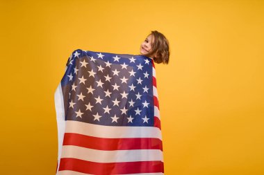 Mutlu çocuk, sarı stüdyo geçmişinde Amerikan bayrağı olan sevimli kız. ABD 4 Temmuz Bağımsızlık Günü 'nü kutladı.