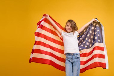 Mutlu çocuk, sarı stüdyo geçmişinde Amerikan bayrağı olan sevimli kız. ABD 4 Temmuz Bağımsızlık Günü 'nü kutladı.