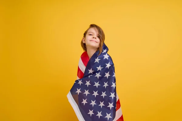 Šťastné dítě, roztomilá dívka s americkou vlajkou na žlutém pozadí studia. USA slaví 4. července, Den nezávislosti. — Stock fotografie