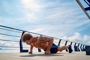 Deniz kenarında şınav çeken genç bir adam. Spor ve sağlıklı yaşam tarzı