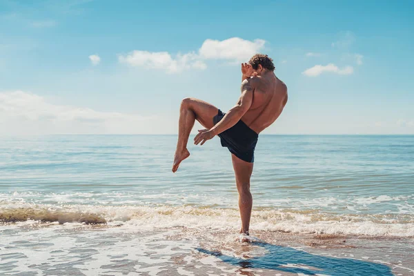 Un muay thai o kickboxer entrenando con boxeo de sombras al aire libre en la orilla del mar —  Fotos de Stock