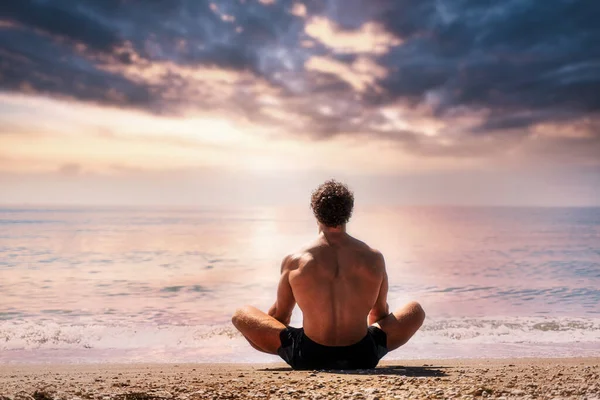 Muž medituje na písečné pláži pohled zezadu — Stock fotografie