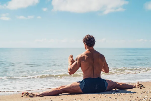 Homme athlétique avec de beaux muscles est assis sur une ficelle dans l'entraînement d'été au bord de la mer — Photo