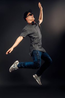 Müzik dinleyip stüdyoda zıplayan bir adamın tam boy görüntüsü. Dikey resim