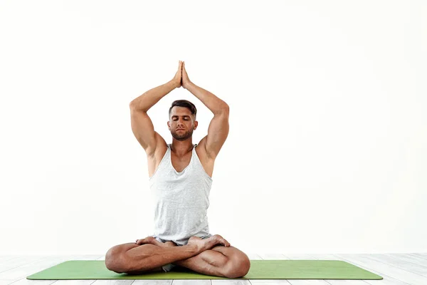 Man yoga maditates in klassieke pose in studio over witte achtergrond — Stockfoto