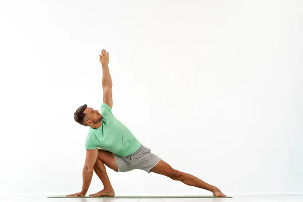 Jovem homem bonito fazendo ioga isolado no fundo branco — Fotografia de Stock