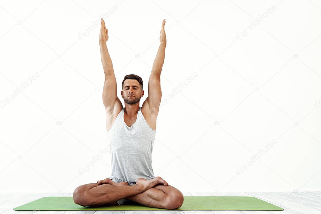 Male yoga maditates in classical pose in studio over white background