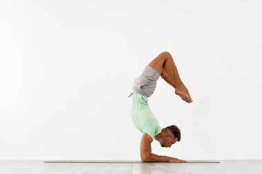 Sportif genç adam amuda kalkıyor, yoga, pilates, fitness eğitimi alıyor, çene dengesinde duruyor Asana