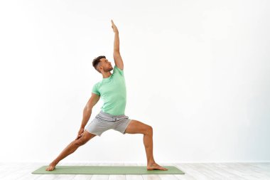 Çekici genç adam beyaz arka planda gelişmiş yoga yapıyor. Bir dizi yoga pozu. Sağlık için. Spor, meditasyon ve yaşam tarzı konsepti